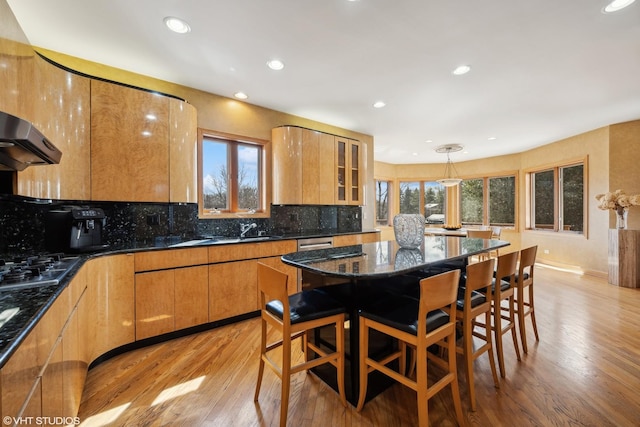 kitchen featuring stainless steel gas cooktop, a sink, light wood-style flooring, and decorative backsplash