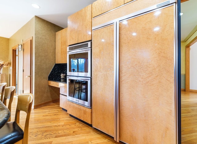 kitchen with baseboards, stainless steel double oven, and light wood-style floors