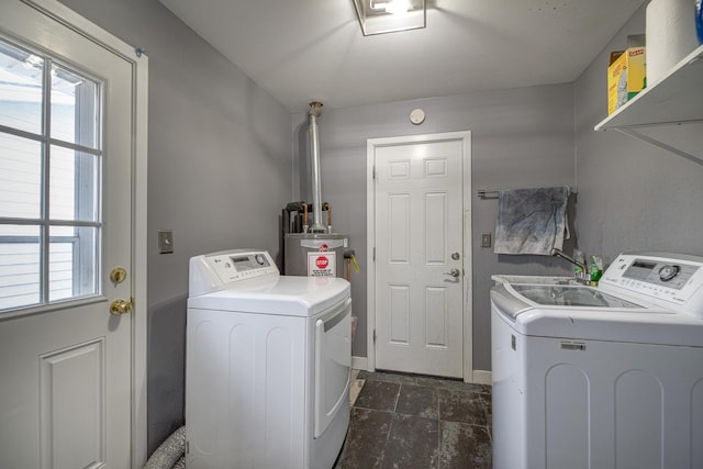 washroom featuring washer and dryer, laundry area, stone finish floor, and baseboards