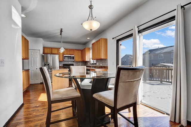 kitchen featuring pendant lighting, tasteful backsplash, stainless steel appliances, and wood-type flooring