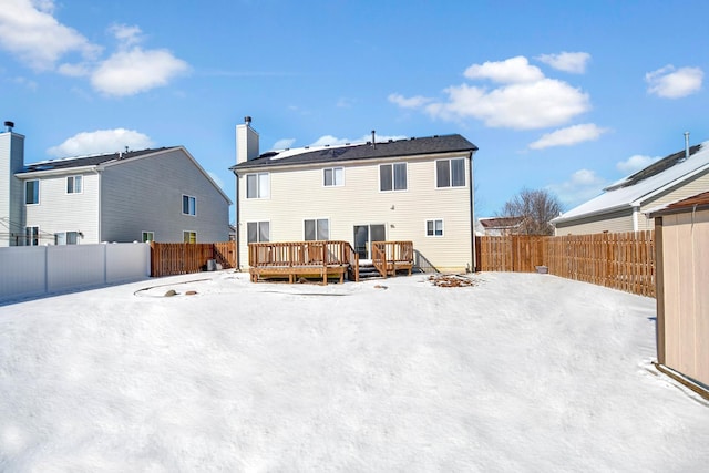 snow covered back of property featuring a wooden deck