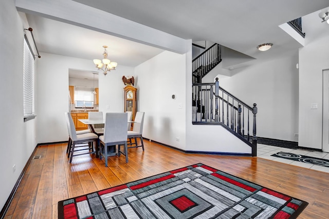 dining room featuring beam ceiling, a chandelier, and light hardwood / wood-style floors