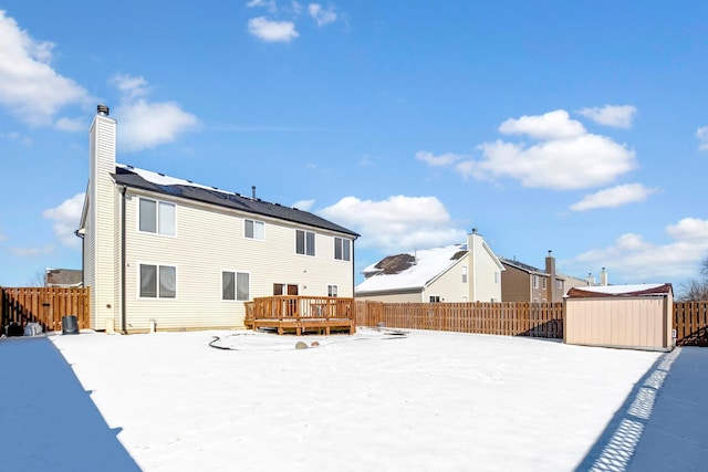 snow covered property with a deck and a storage shed