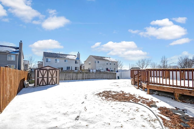 yard covered in snow featuring a wooden deck and a storage shed