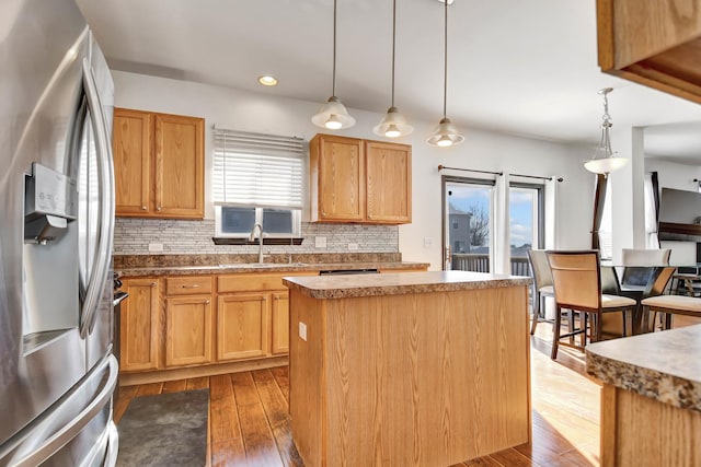 kitchen with hanging light fixtures, sink, a center island, and stainless steel refrigerator with ice dispenser