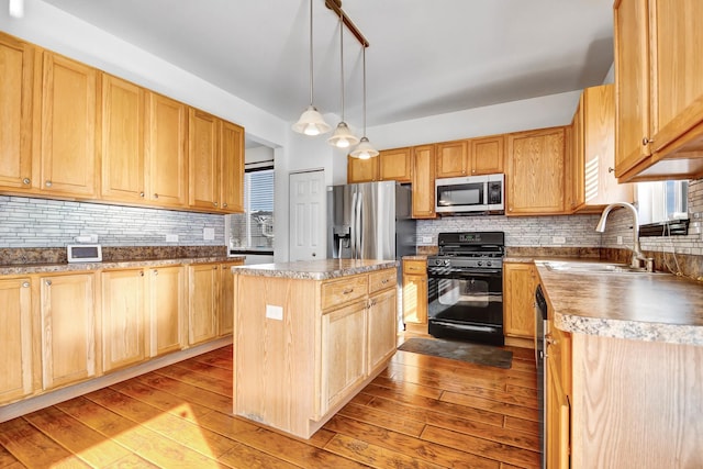 kitchen featuring sink, decorative light fixtures, light wood-type flooring, appliances with stainless steel finishes, and a kitchen island