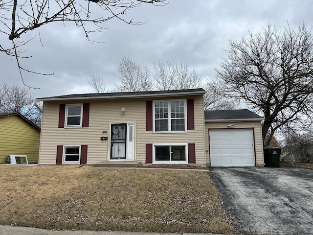 bi-level home featuring a garage and a front lawn