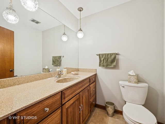 bathroom featuring toilet, vanity, baseboards, visible vents, and tile patterned floors