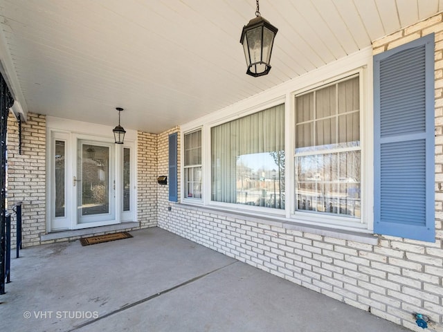 doorway to property with a porch and brick siding