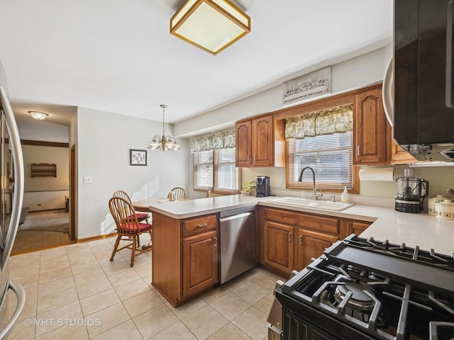 kitchen featuring stainless steel appliances, brown cabinets, a sink, and a peninsula