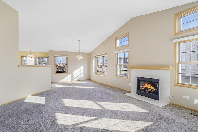 unfurnished living room with high vaulted ceiling, an inviting chandelier, light colored carpet, and a tiled fireplace