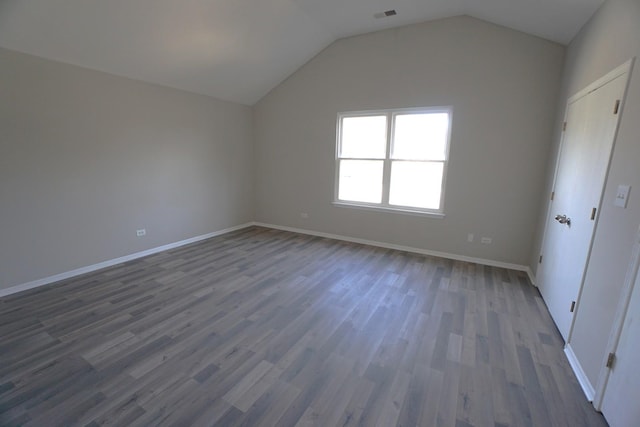 additional living space with dark wood-type flooring, visible vents, vaulted ceiling, and baseboards