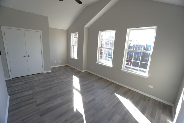 unfurnished bedroom featuring dark wood-type flooring, a ceiling fan, baseboards, vaulted ceiling, and a closet