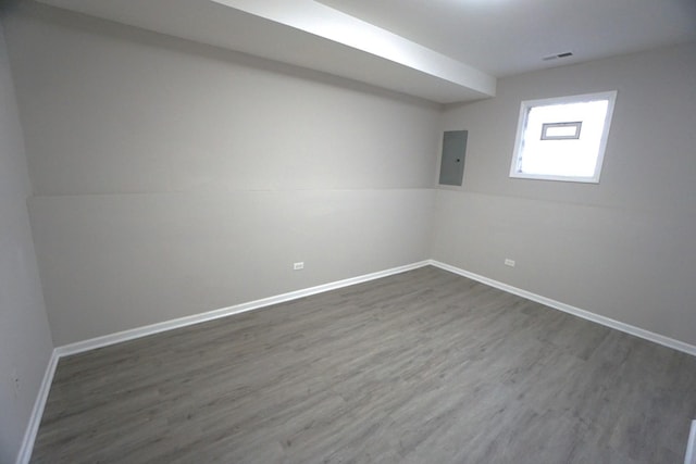 spare room featuring dark wood-type flooring, electric panel, visible vents, and baseboards