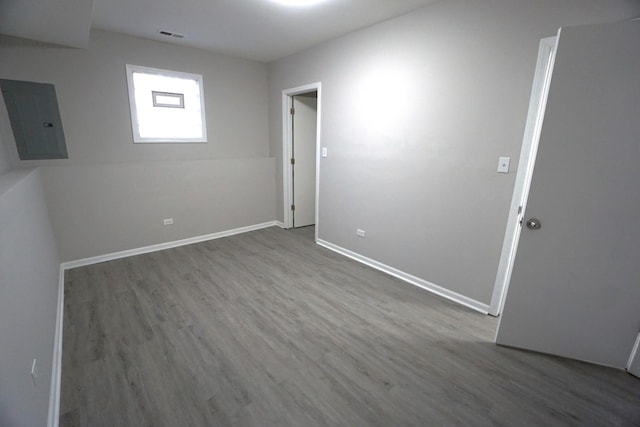 spare room featuring electric panel, baseboards, and wood finished floors