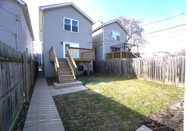 back of property with a wooden deck, stairway, a fenced backyard, and a lawn