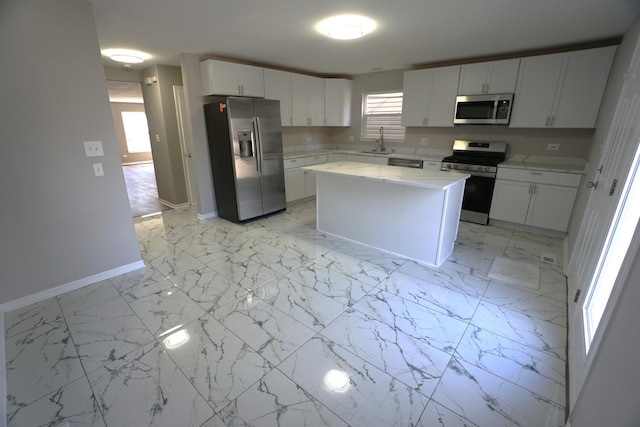 kitchen with a center island, light countertops, appliances with stainless steel finishes, white cabinetry, and a sink