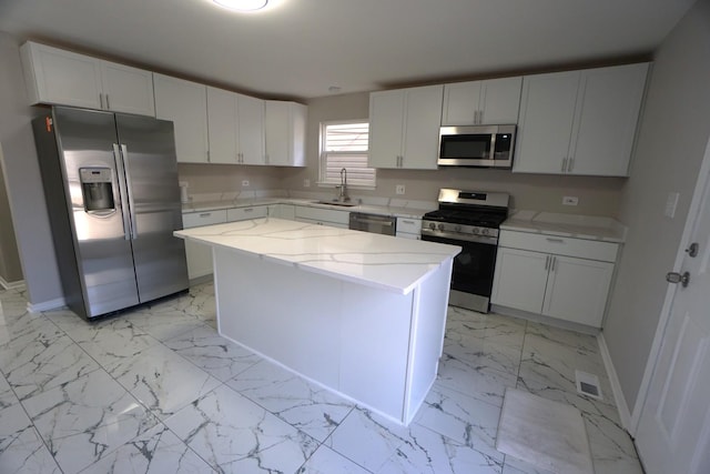 kitchen with stainless steel appliances, a center island, marble finish floor, and white cabinets