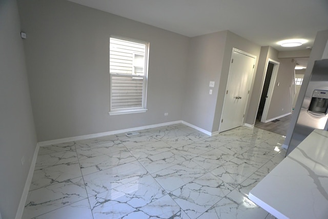 empty room featuring marble finish floor and baseboards