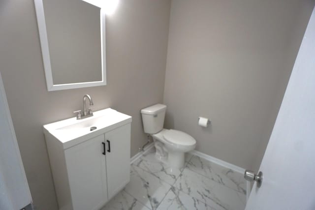 bathroom with marble finish floor, baseboards, vanity, and toilet