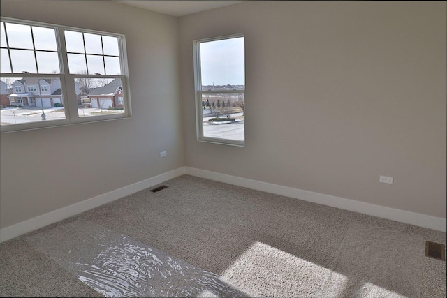 empty room featuring visible vents, baseboards, and carpet flooring