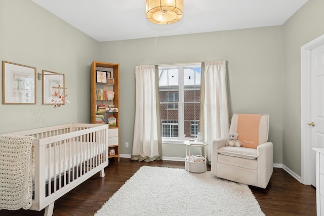 bedroom with a nursery area and dark hardwood / wood-style floors