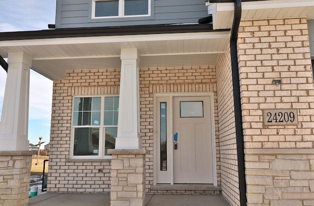 property entrance featuring covered porch and brick siding