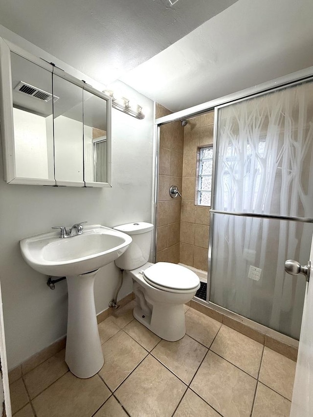 bathroom featuring tile patterned flooring, a shower with door, and toilet