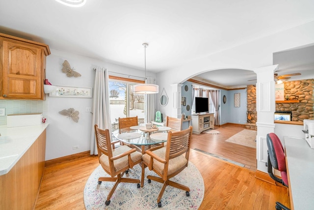 549 Beachview Dr, Lake Holiday, IL 60552 - dining area with a fireplace, baseboards, ornate columns, light wood-type flooring, and arched walkways