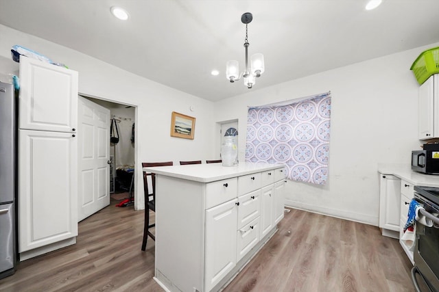 kitchen with light hardwood / wood-style floors, hanging light fixtures, a breakfast bar, and white cabinets