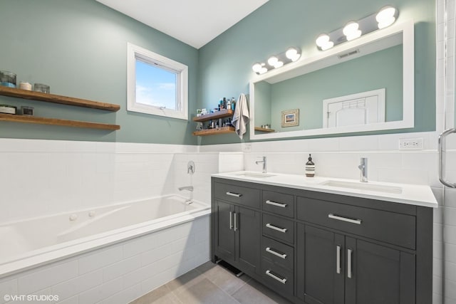 bathroom with vanity, tile patterned flooring, tile walls, and tiled tub