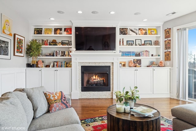 living room featuring light wood-type flooring and built in shelves