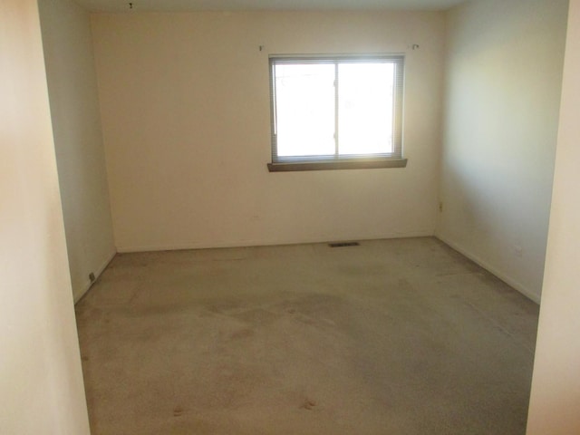 spare room featuring visible vents and light carpet