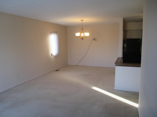 carpeted spare room featuring visible vents and a chandelier