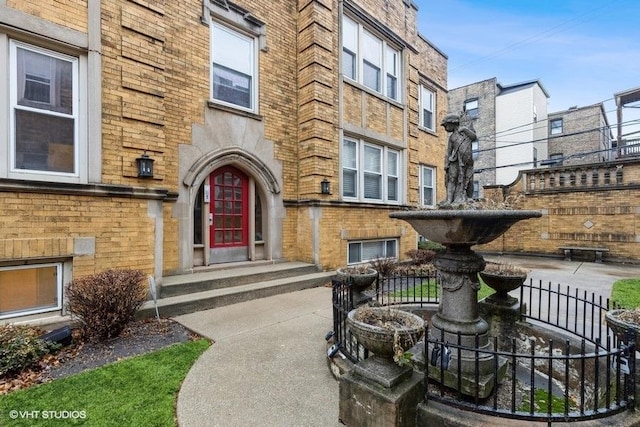 property entrance with brick siding and fence