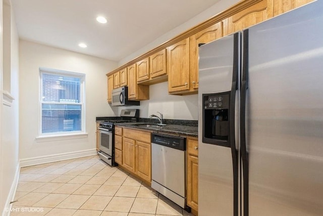 kitchen featuring light tile patterned floors, stainless steel appliances, recessed lighting, a sink, and dark stone countertops