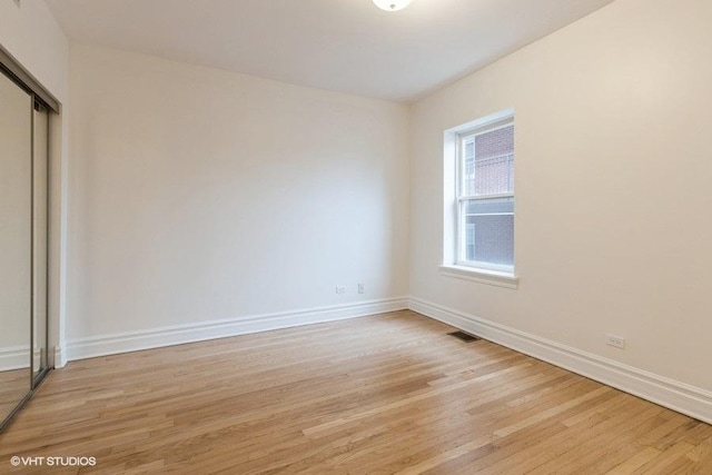 unfurnished room featuring light wood-style floors, visible vents, and baseboards