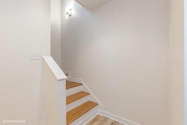 staircase featuring baseboards and wood finished floors