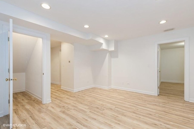 finished below grade area with light wood-type flooring, visible vents, baseboards, and recessed lighting