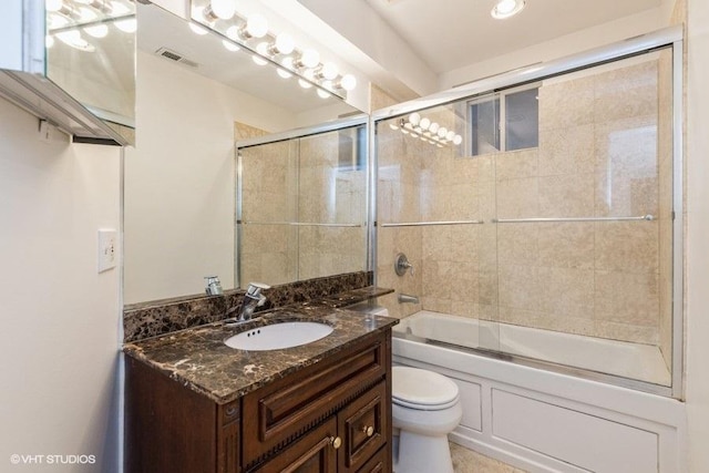 bathroom featuring toilet, vanity, visible vents, and enclosed tub / shower combo