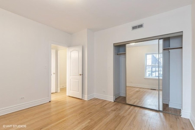 unfurnished bedroom featuring light wood finished floors, baseboards, visible vents, and a closet