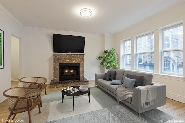 living room with ornamental molding, wood finished floors, a high end fireplace, and baseboards