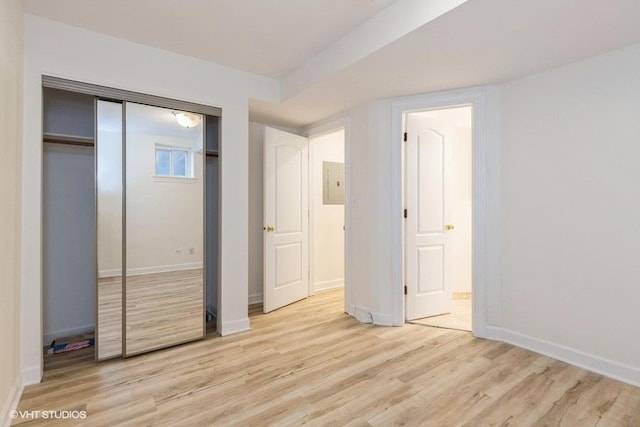 unfurnished bedroom featuring light wood-style floors, baseboards, and a closet