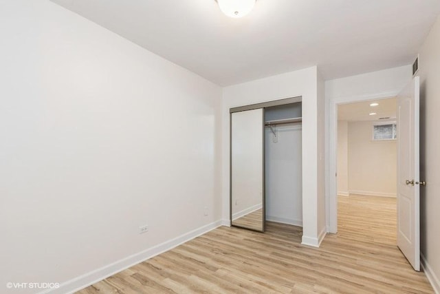 unfurnished bedroom with a closet, visible vents, light wood-style flooring, and baseboards