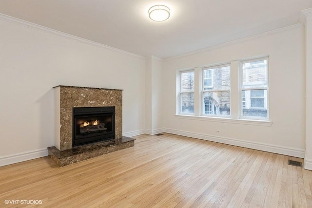 unfurnished living room featuring light wood-type flooring, visible vents, and ornamental molding