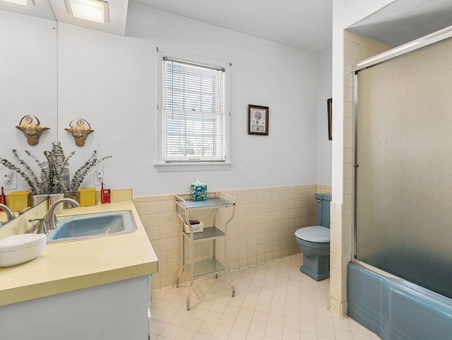 full bathroom featuring tile patterned floors, toilet, tile walls, vanity, and enclosed tub / shower combo