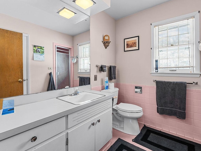 bathroom with tile patterned floors, vanity, tile walls, and a wealth of natural light