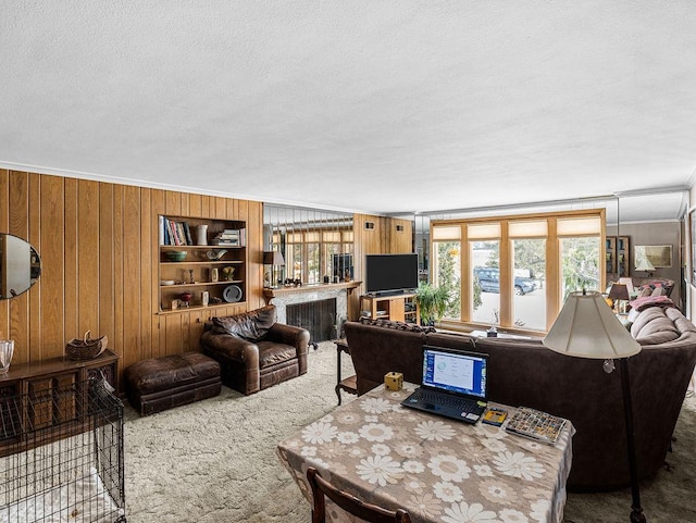 carpeted living room featuring crown molding, built in shelves, a textured ceiling, and wood walls