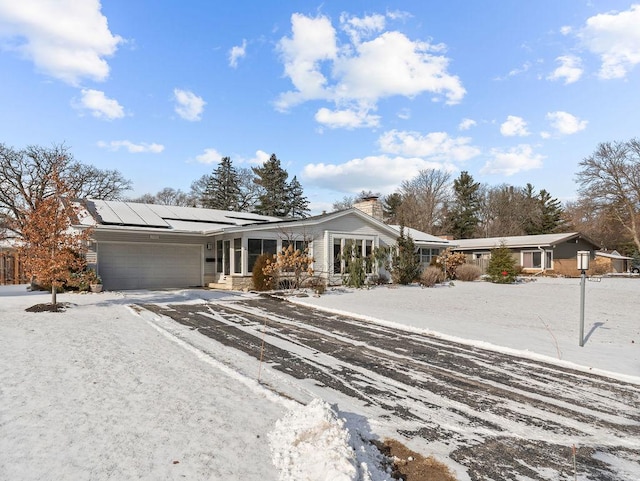 ranch-style home featuring a garage and solar panels