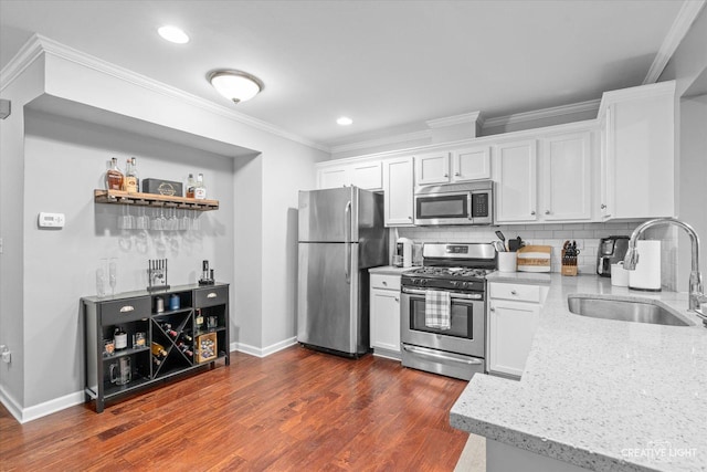 kitchen featuring tasteful backsplash, appliances with stainless steel finishes, light stone counters, crown molding, and a sink